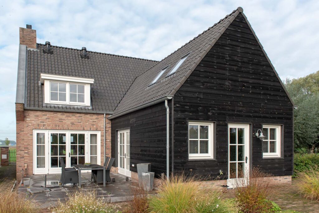 Foto van stenen nieuwbouw huis met aan achterzijde uitbouw met zwarte houten gevel