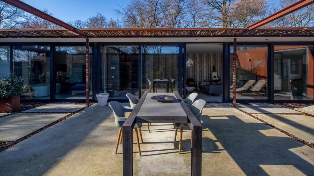 Foto van terras met tafel en stoelen bij stalen boshuis